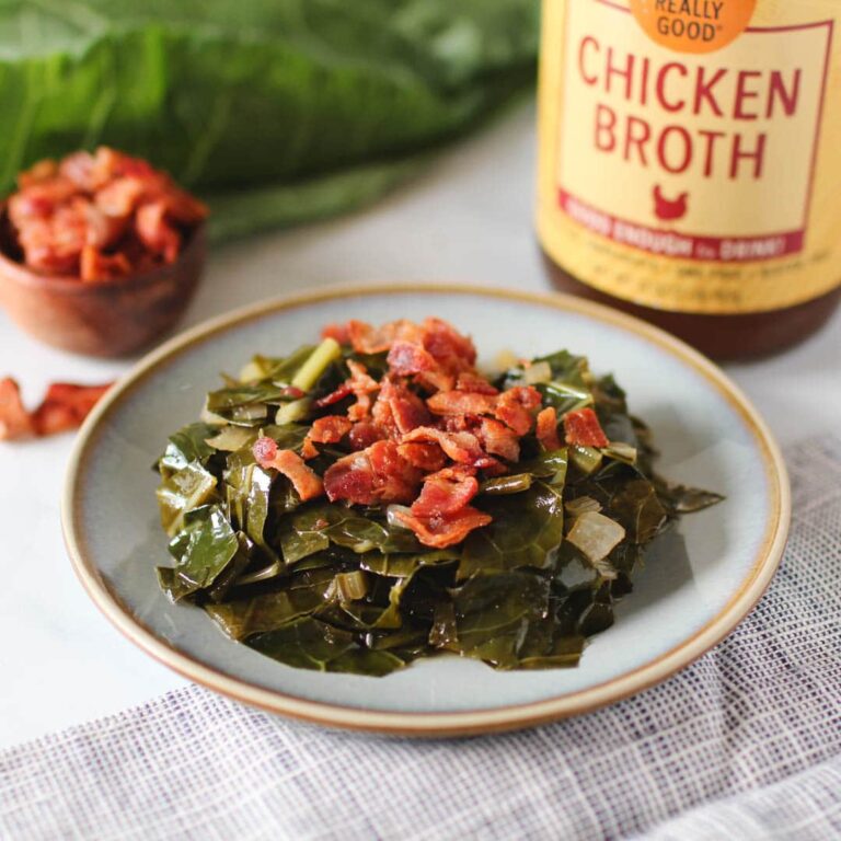 Cooked collard greens topped with diced crispy bacon in front of a jar of Zoup Chicken Broth.